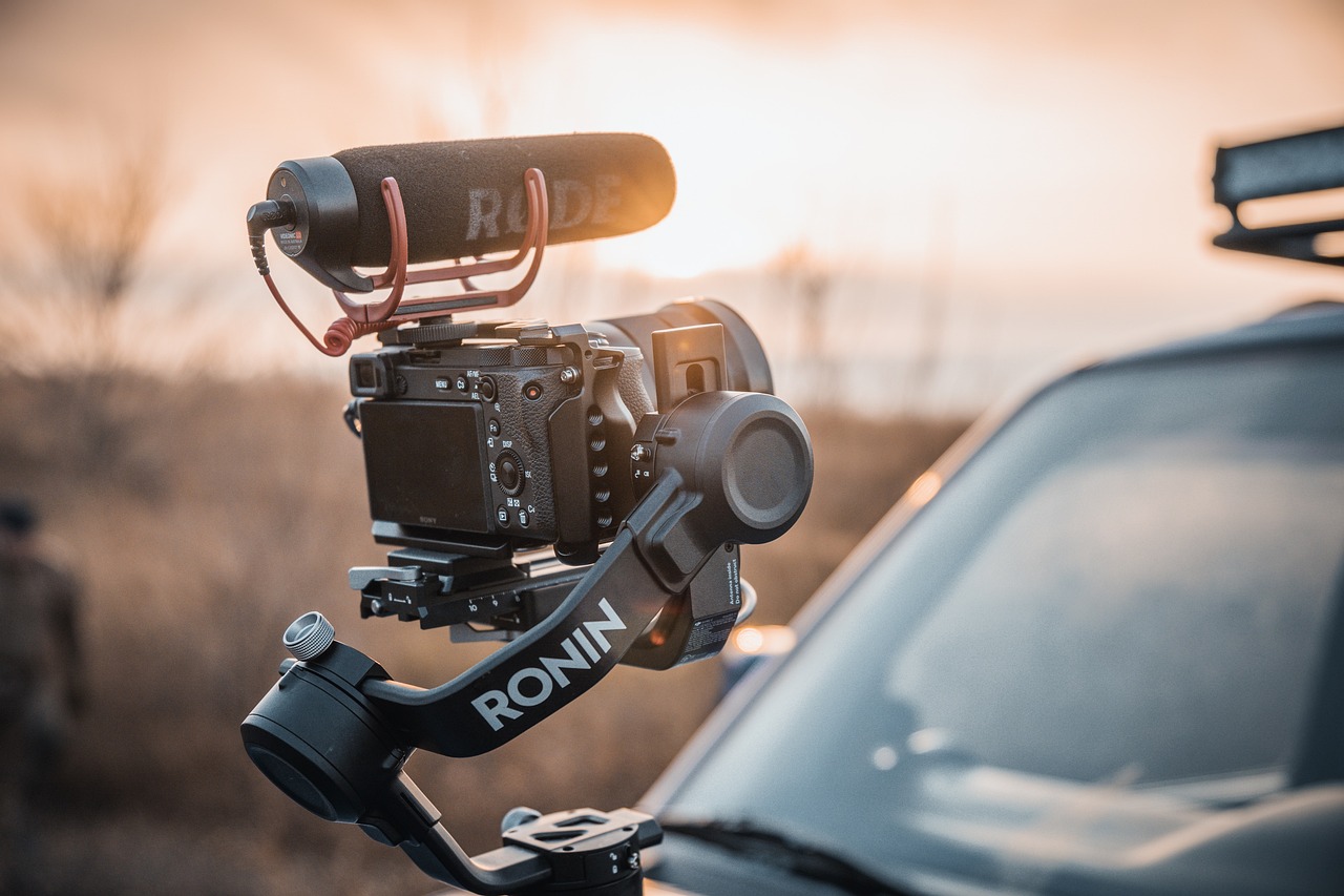 Movie camera with mounted microphone near a car in the wilderness