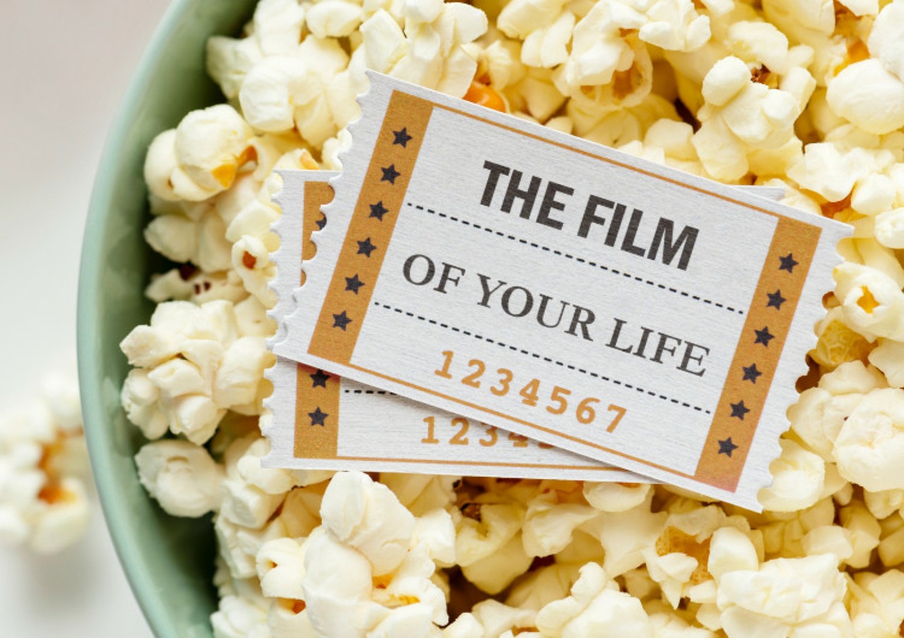 A bowl of popcorn with movie tickets on top